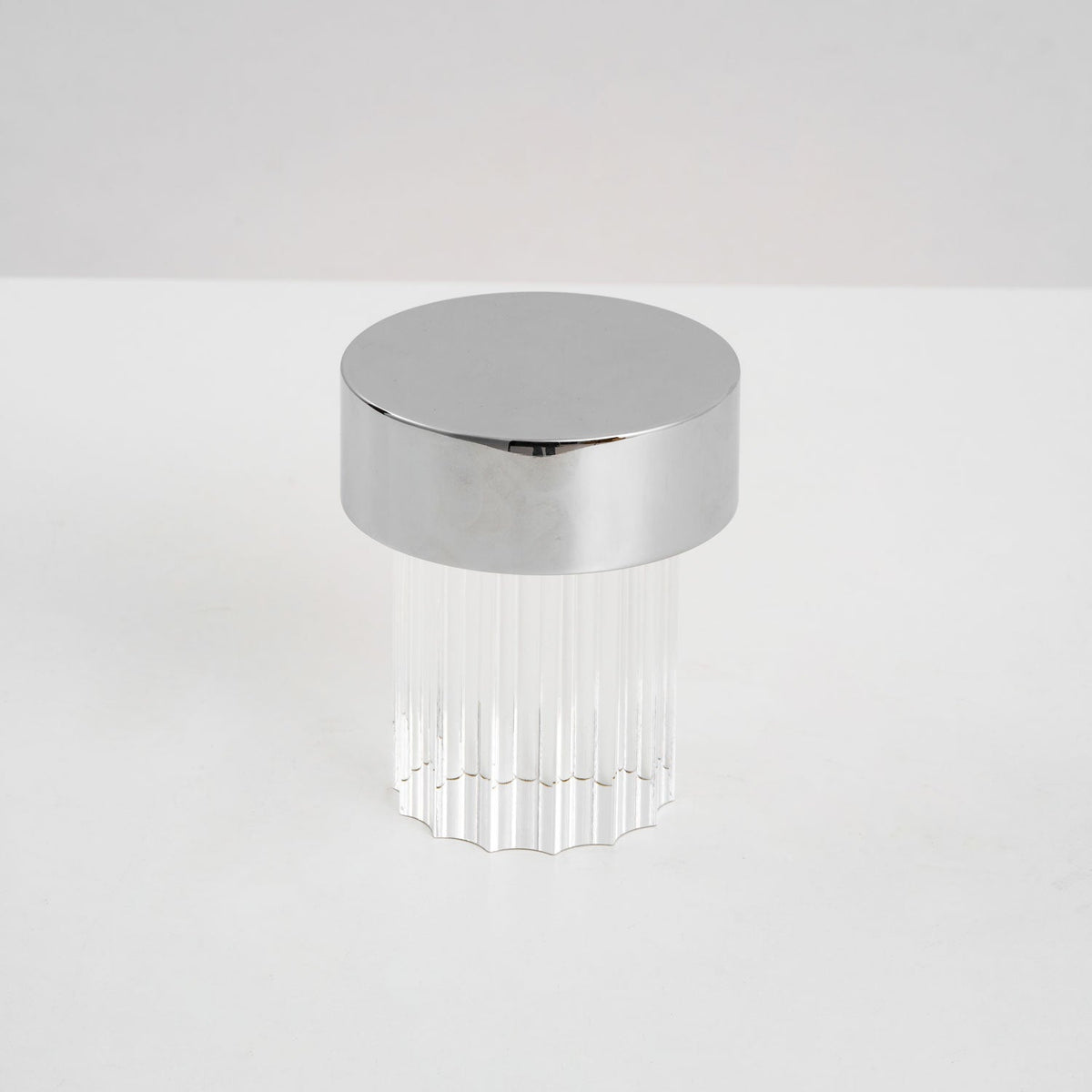 A fluted Clérachic lamp with a chrome cap on a pale tabletop, unlit, seen from slightly above.