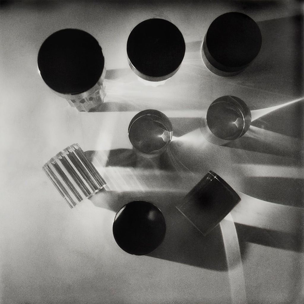 Overhead black-and-white shot of several Clérachic lamps lying and standing on their sides, casting long shadows and light beams.