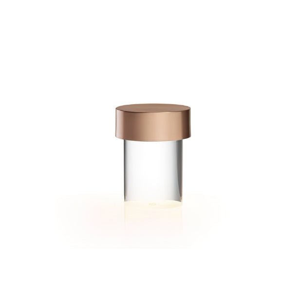 This Clérachic lamp on white, with a rose gold cap over clear smooth glass and a warm glow at its base.