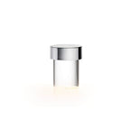 This Clérachic lamp on white, with a polished chrome cap, clear smooth glass and a soft warm glow at the foot.