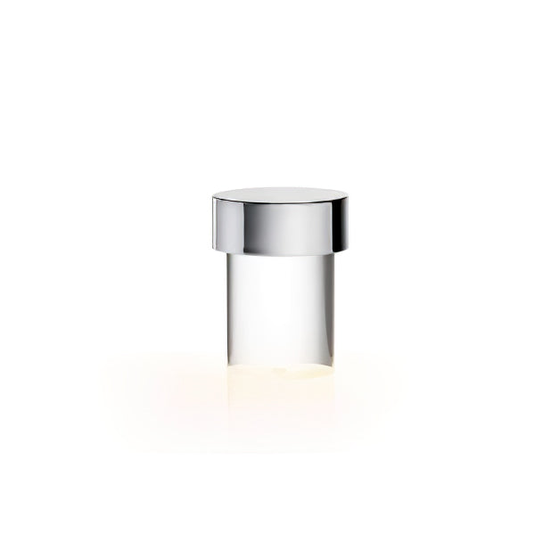 This Clérachic lamp on white, with a polished chrome cap, clear smooth glass and a soft warm glow at the foot.