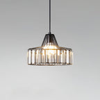 Close view of a black wire-framed crystal drum pendant from Clérachic, with its bulb glowing against a soft grey gradient.