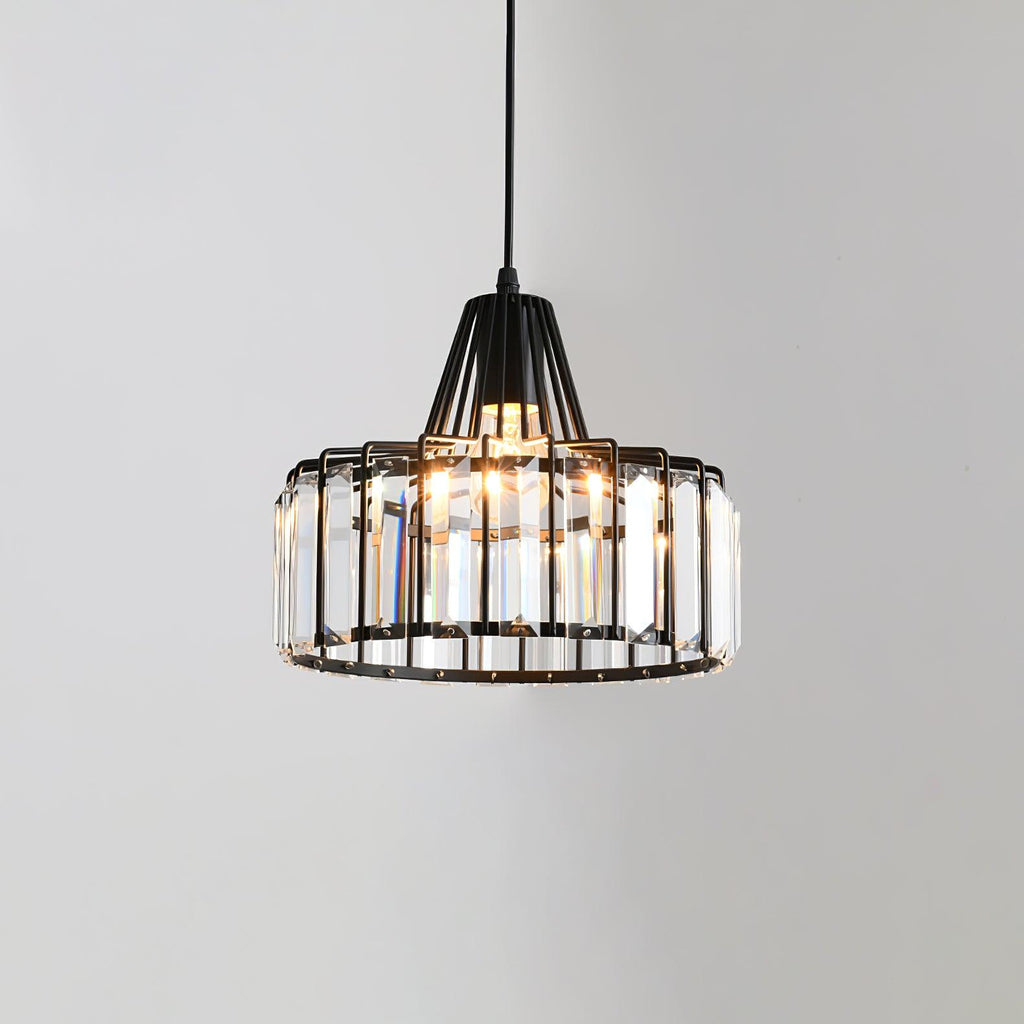 Black-framed Clérachic pendant with tall clear crystal prisms around the drum, lit from within, against a pale grey wall.
