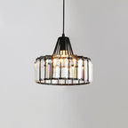 Black-framed Clérachic pendant with tall clear crystal prisms around the drum, lit from within, against a pale grey wall.
