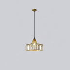 Gold crystal drum pendant from Clérachic on a gold ceiling plate, hung on a long black cable against a pale lilac-grey wall.