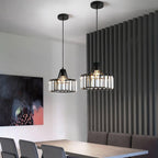 Two black crystal drum pendants from Clérachic, hung at different heights in a modern room with a dark slatted wall and a bold painting.