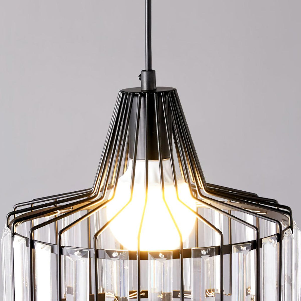 Underside view of the bulb and black wire cage of this Clérachic crystal drum pendant, with clear prisms around the lower edge.