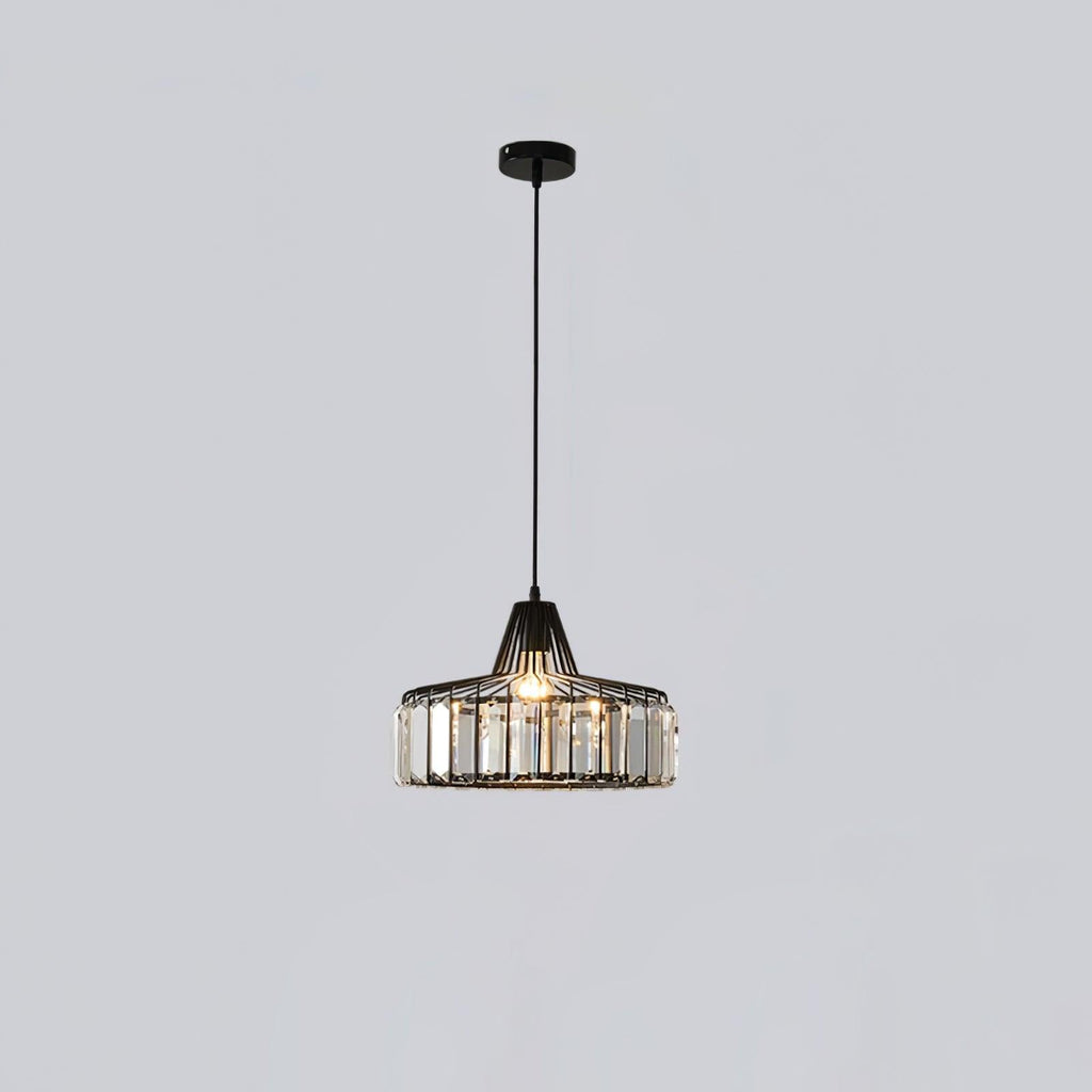 Small black crystal drum pendant from Clérachic on a black ceiling plate, hanging on a long cable against a pale grey wall.