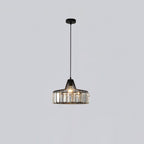 Small black crystal drum pendant from Clérachic on a black ceiling plate, hanging on a long cable against a pale grey wall.