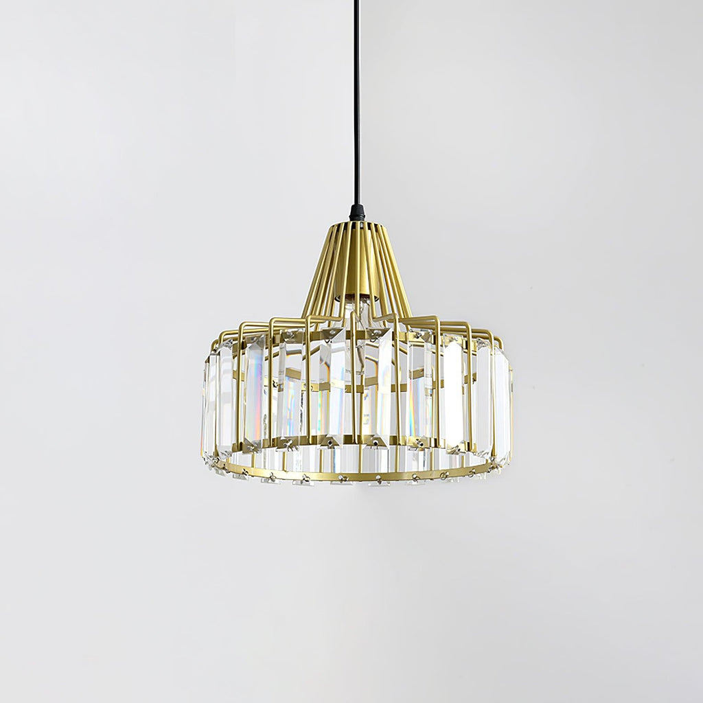 Gold crystal drum pendant from Clérachic with clear prisms and a gold cage, seen against a pale grey wall.
