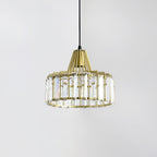 Gold crystal drum pendant from Clérachic with clear prisms and a gold cage, seen against a pale grey wall.
