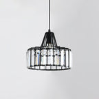 Black wire-framed Clérachic pendant with tall clear crystal prisms around the drum, unlit, against a pale grey wall.