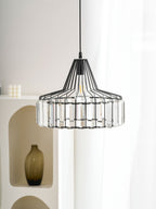 Black wire-framed crystal drum pendant from Clérachic hangs in front of a white arched shelf unit with a dark glass vase.