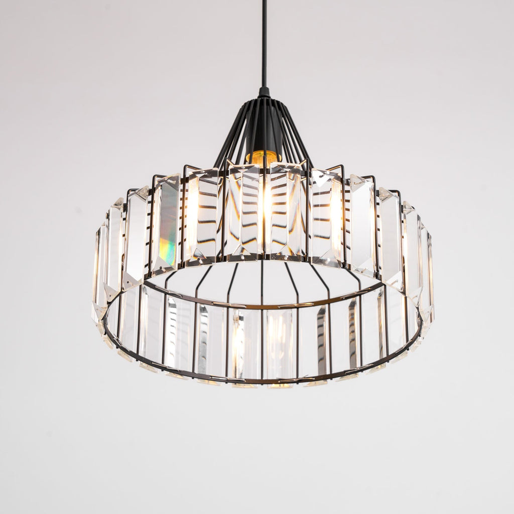 Upward view into the black drum pendant from Clérachic, showing the open base and the clear prisms ringed around the frame.