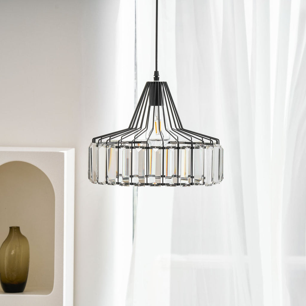 Close, slightly raised view of a black crystal drum pendant from Clérachic, with an arched white shelf and a green glass vase behind.