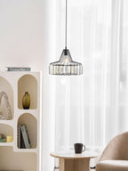 Black crystal drum pendant from Clérachic hangs by sheer curtains, above an arched white shelf unit and a table with a black cup.