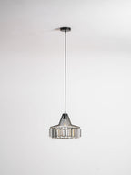 Black crystal drum pendant from Clérachic on a black ceiling plate and long cable, hanging against a pale grey backdrop.