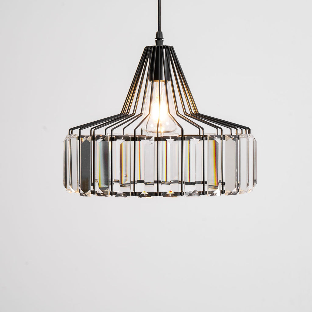 Large black crystal drum pendant from Clérachic, lit, seen close with every clear prism visible against a pale backdrop.