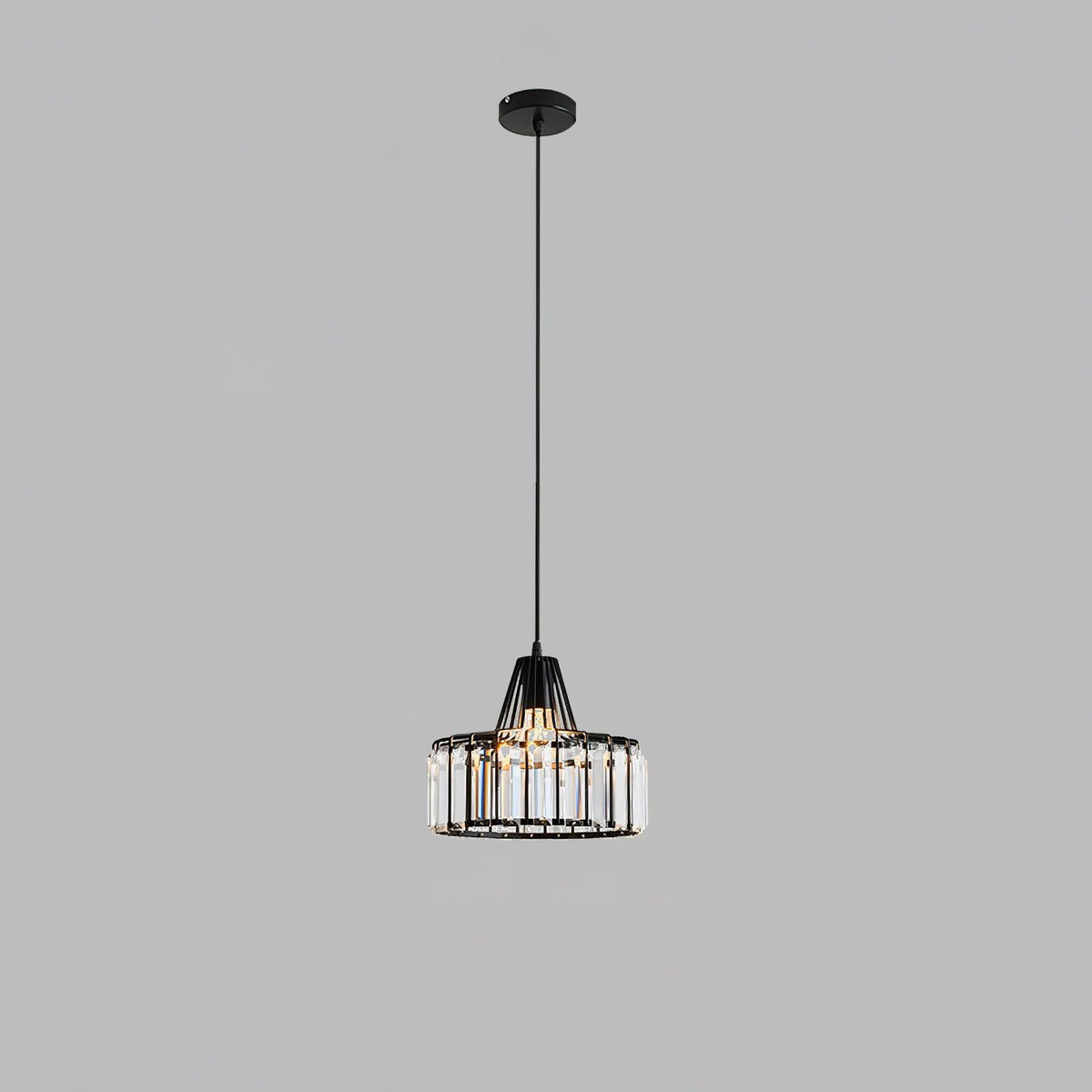 Black crystal drum pendant from Clérachic on a black ceiling plate and long cable, against a flat grey backdrop.