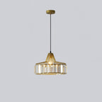 Gold crystal drum pendant from Clérachic with a gold ceiling plate, lit, hanging on a long black cable against a pale grey backdrop.