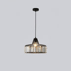 Black crystal drum pendant from Clérachic on a black ceiling plate, lit, hanging on a long cable against a light grey backdrop.