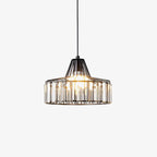Black metal drum pendant from Clérachic with clear crystal prisms and a lit bulb, hanging on a light backdrop.