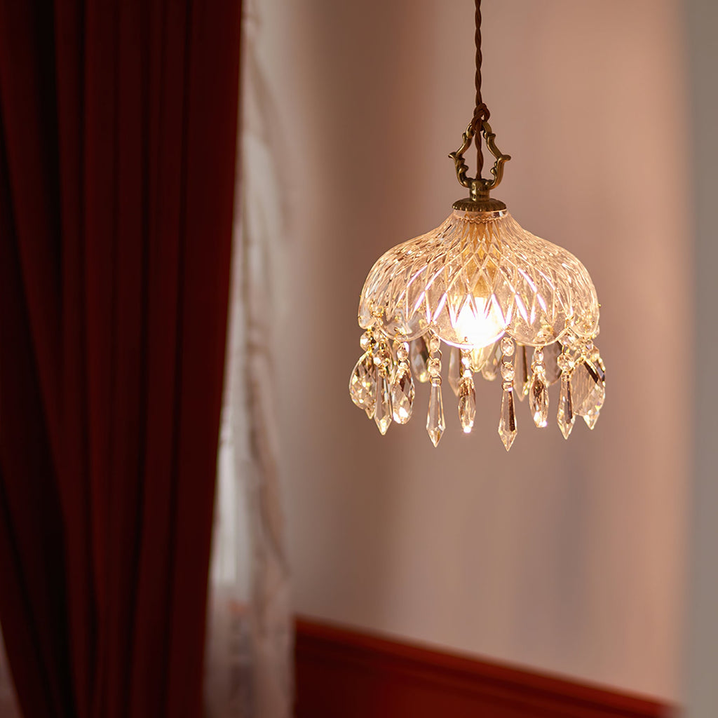 Lit against a dusty-pink wall beside a red curtain, this Clérachic pendant light glows through cut glass and a fringe of crystal drops.
