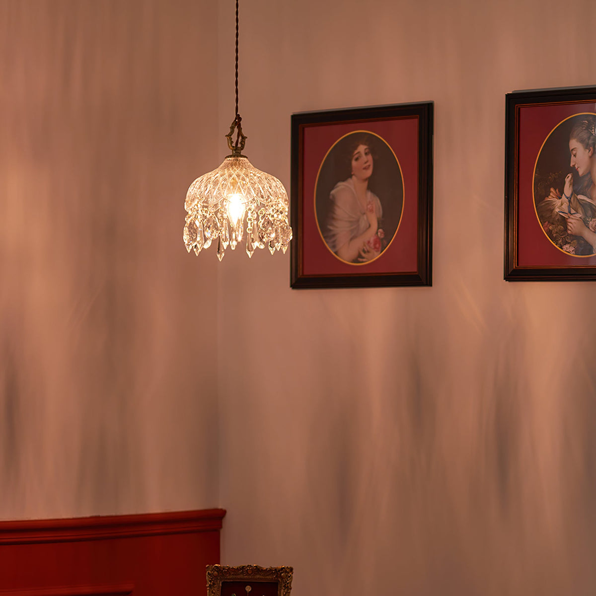 This Clérachic pendant light hangs small and glowing on a rose-toned wall, with two framed portraits in red mounts beside it.