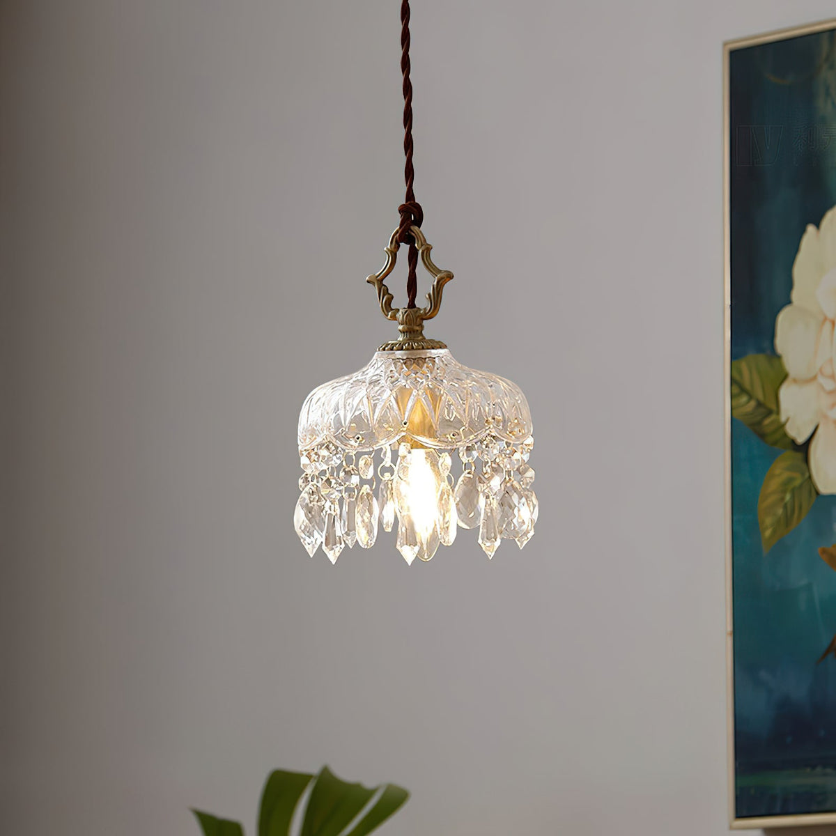 This Clérachic pendant light hangs against a grey wall beside a large blue floral painting, a leaf just in view below.
