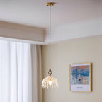 Wide view of this Clérachic pendant light hanging low in a cream room with white curtains, ceiling cornice and a framed seascape.