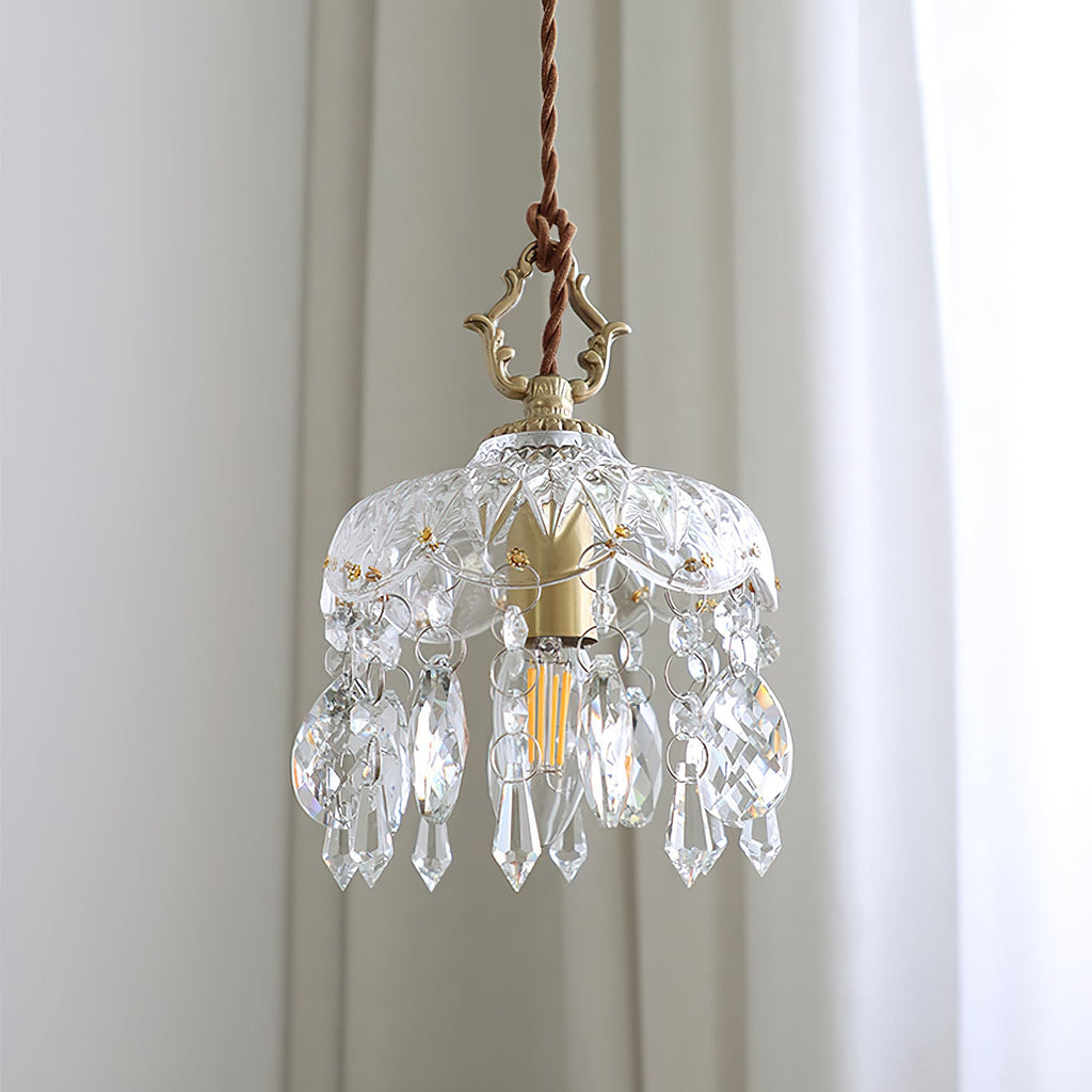 Close view of the cut-glass dome, filament bulb and teardrop crystals of this Clérachic pendant light against white curtains.