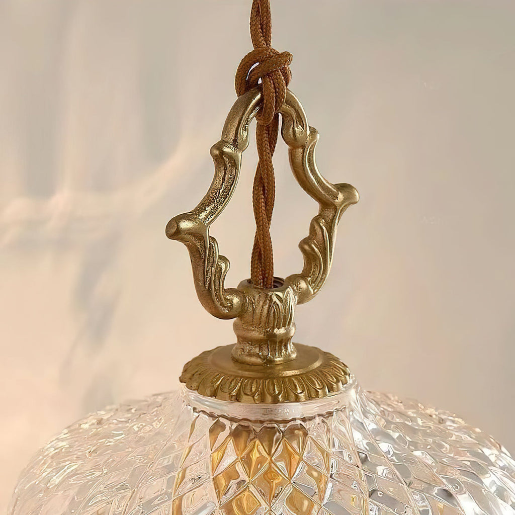 Close view of the carved brass hanger and twisted cord where this Clérachic pendant light meets its glass dome.