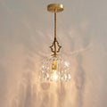 Lit against a softly rippled wall, this Clérachic pendant light hangs from a round gold ceiling plate on a twisted cord.