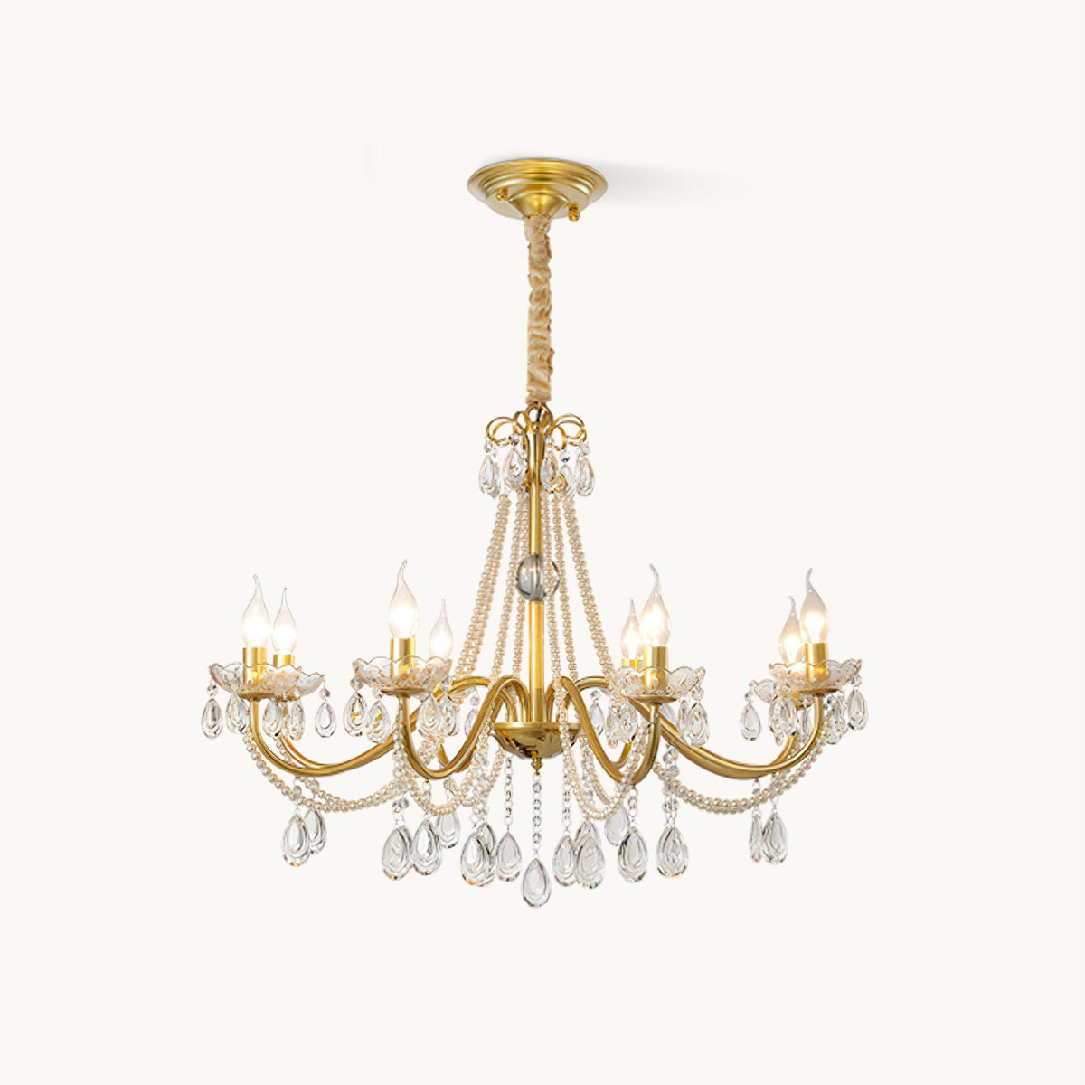 This Clérachic crystal chandelier on a plain white backdrop, with gold arms, strands of pearl beads and teardrop crystals below.
