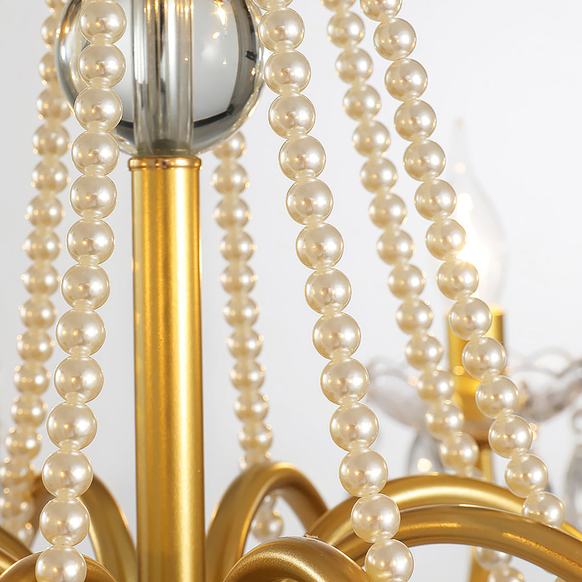 Close view of the gold central column, a glass ball and strands of pearl beads on this Clérachic chandelier.