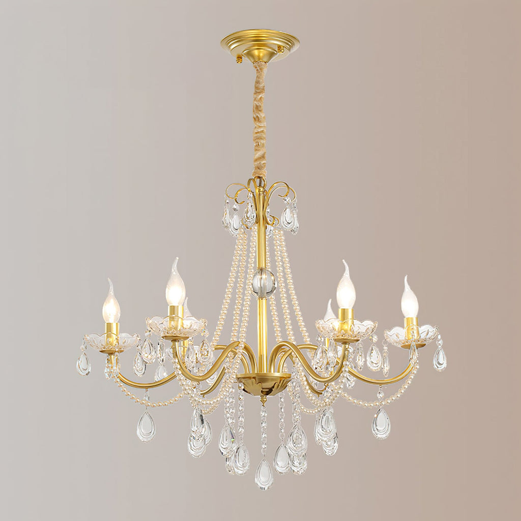 A Clérachic gold chandelier with a gold ceiling canopy and a wrapped chain, its candle bulbs lit, against a soft rose-grey backdrop.