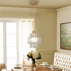 Clérachic gold crystal pendant on a white cord above a set dining table with hydrangeas and tufted seating.