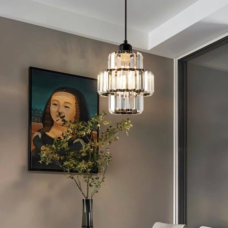 Clérachic black crystal pendant beside a framed painting and a tall leafy stem in a softly lit room.