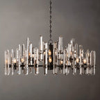 Clérachic widest round chandelier of clear crystal rods on a matte black frame, with many candle bulbs, on a grey ground.