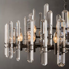 Clérachic close view of crystal rods, matte black arms and candle-style bulbs on a round chandelier.