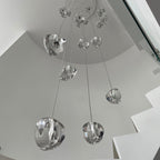 Looking up from below, this Clérachic pendant shows large clear glass heads on long wires dropping through a white stairwell.