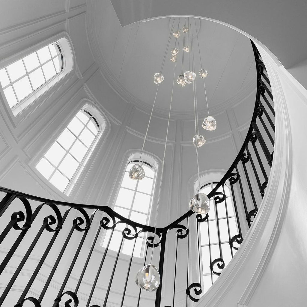 In a black-and-white photo, this Clérachic pendant hangs in a domed stairwell with arched windows and a wrought-iron balustrade.