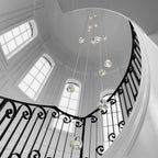 In a black-and-white photo, this Clérachic pendant hangs in a domed stairwell with arched windows and a wrought-iron balustrade.
