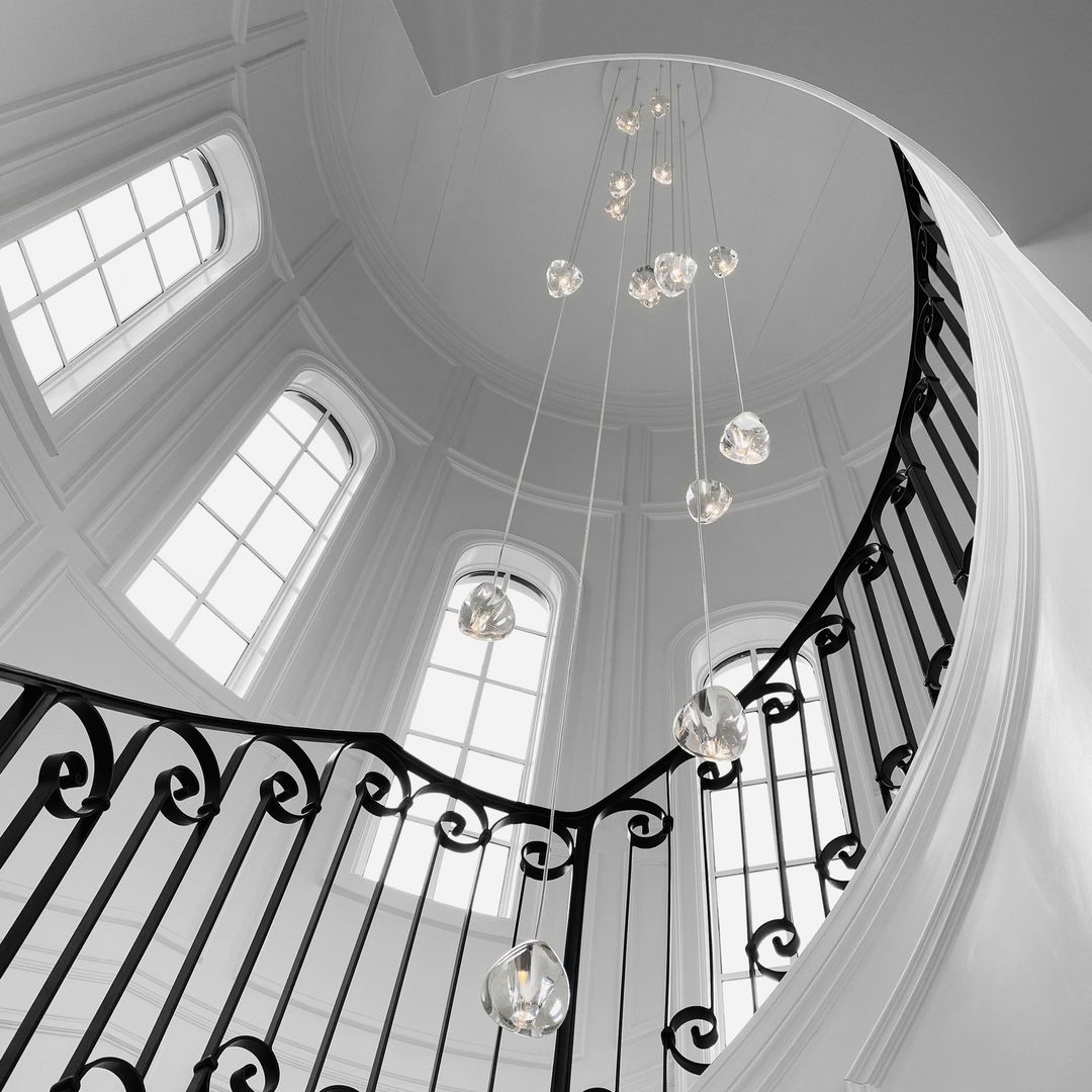 In a black-and-white photo, this Clérachic pendant hangs in a domed stairwell with arched windows and a wrought-iron balustrade.