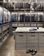 Clear glass heads of this Clérachic pendant hang in a walk-in wardrobe with glass-fronted shelves and a central island.