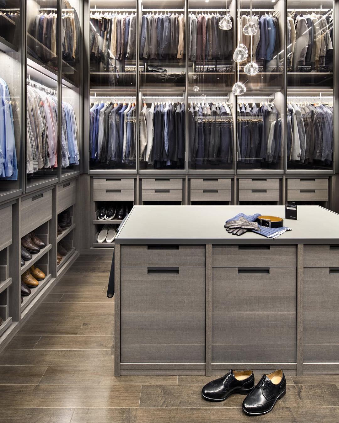 Clear glass heads of this Clérachic pendant hang in a walk-in wardrobe with glass-fronted shelves and a central island.