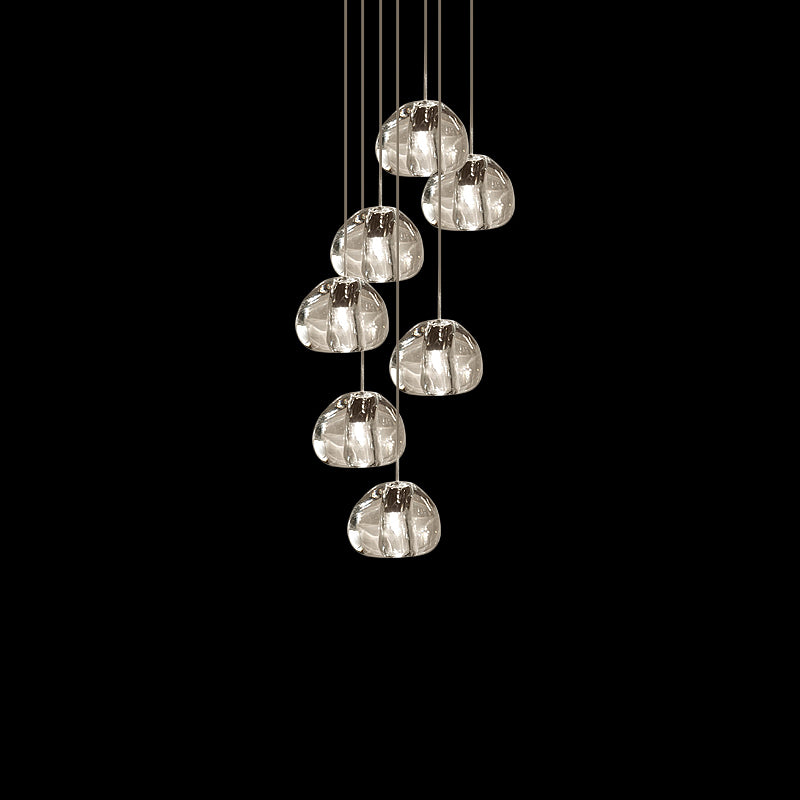 Seven clear glass heads of this Clérachic pendant hang together on fine cords against a black backdrop.
