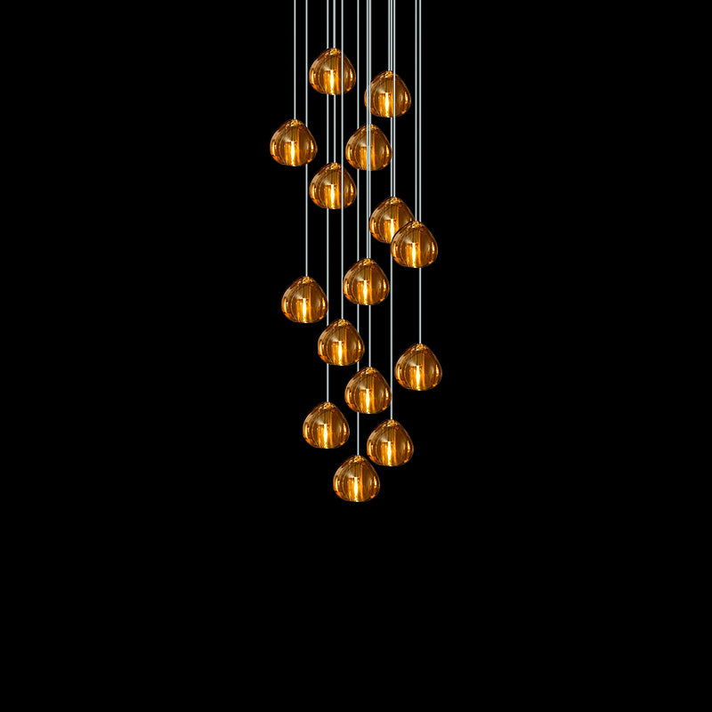 A dense cluster of amber glass heads from this Clérachic pendant hangs on cords against a black background.