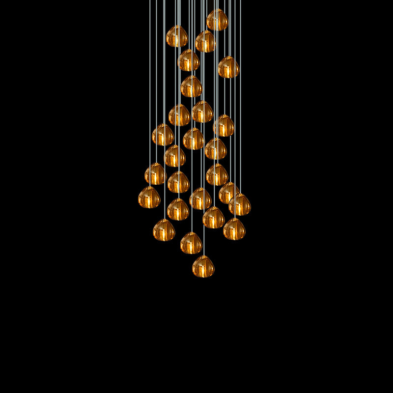 A large group of amber glass heads on this Clérachic pendant hangs on long cords, shown against a black background.