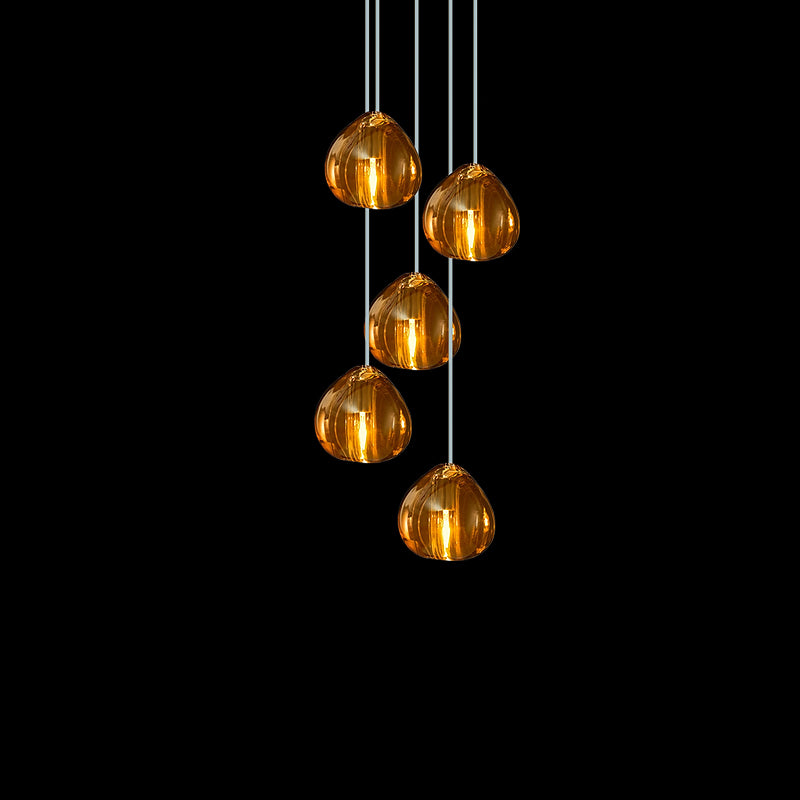 Five amber glass heads on this Clérachic pendant hang in a staggered group on pale cords against a black background.